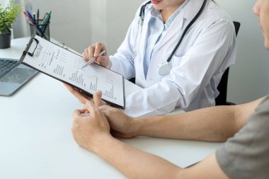 Doktor, teşhis, tıp ve klinikteki hastalara tavsiye verme konularında hastalara hastalık ve semptomları açıklayan bir belgeye işaret ediyor.