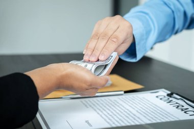 Yasa dışı ve ahlaksız yolsuzluk projesiyle ilgili sözleşmeyi imzaladıktan sonra bir adamın iş adamından rüşvet aldığı yakın plan.