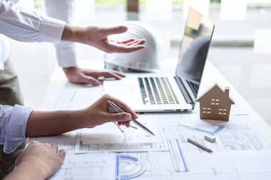 İnşaat mühendisi veya mimar, çalışma sahasındaki mimari projenin çizim ve çizim toplantısına ilişkin bilgileri incelerken bir planı da tartışır..