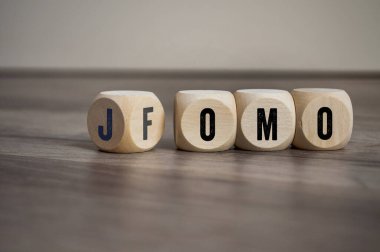 Küpler, zarlar ya da bloklar FOMO 'yu kaybetme korkusu ve ahşap arka planda kaçırmanın sevinci.