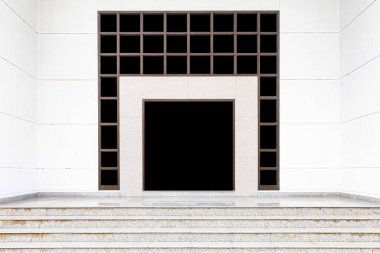 Binanın girişinde büyük alüminyum kapılar ve beyaz taş duvarlar var.