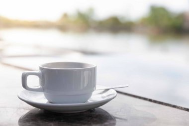 Kahve fincanlarını nehir kenarındaki kahvaltı masasına koydum..