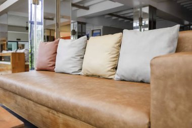 Evdeki resepsiyonda kahverengi deri kanepe ve yastıklar.