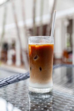 Bir bardakta buzlu kapuçino ve modaya uygun bir kafede pipetler.