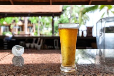 Bahçe tezgahında uzun bira bardağı var.