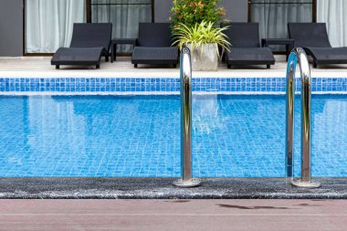 Geniş yüzme havuzu ve villanın içinde kahverengi taş zemin.