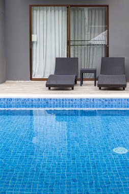 Geniş yüzme havuzu ve villanın içinde kahverengi taş zemin.