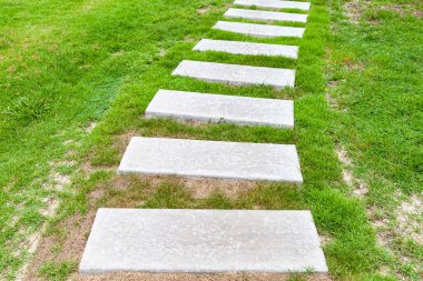 Bahçedeki yeşil çimlerde desenli beyaz granit yürüyüş yolları.