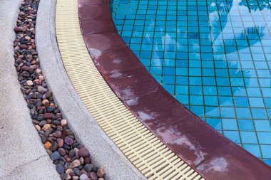 Geniş yüzme havuzu ve villanın içinde kahverengi taş zemin.