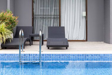 Geniş yüzme havuzu ve villanın içinde kahverengi taş zemin.