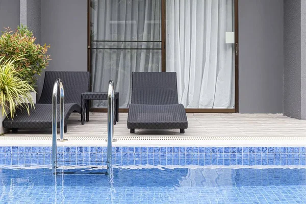 Geniş yüzme havuzu ve villanın içinde kahverengi taş zemin.