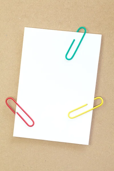 Color metal paper clip and blank white paper note — Stock Photo, Image