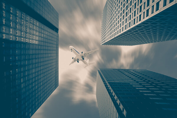 Airplane flying over high rise business buildings