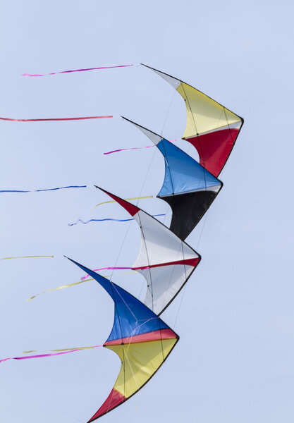Colorful kites flying  in single file in the sky