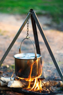 Yürüyüşte bir kazanda kamp ateşinde yemek pişirmek.
