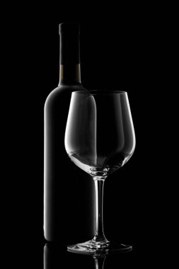 Kırmızı şarap şişesi ve şarap kadehi siyah arka planda izole edilmiş.