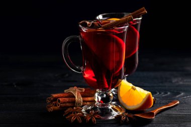 Baharatlı şarap, cam bardaklara dökülüyor. Ahşap, koyu bir arka planda, metin için yer var.