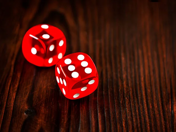 Red dice on dark wooden table. Background for casino games, gambling, luck or randomness