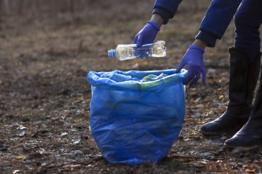 Kız plastik toplar. Çöp torbasına koyuyor. Plastik atıklardan kaynaklanan çevre kirliliği sorunu... Ekolojik kirlilik. Ekoloji sorunu.