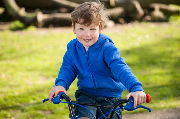 Niño feliz en su moto en el parque —  Fotos de Stock