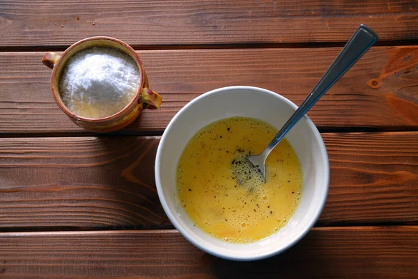 Seramik bir kasede süt ve baharatlı çiğ yumurta sarısı çırpılmış yumurta yapar. 