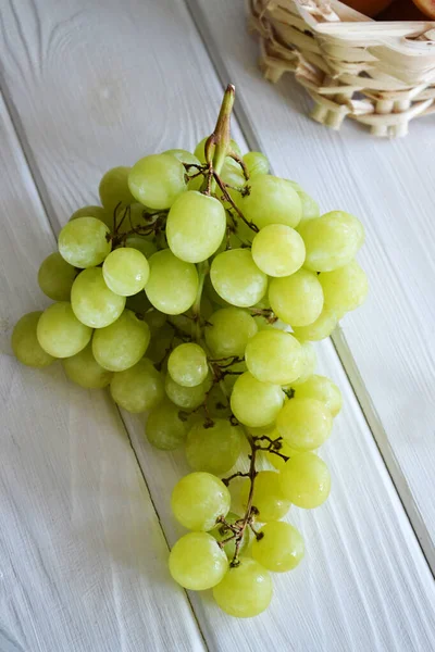 Beyaz ahşap arka planda tek demet yeşil üzüm.