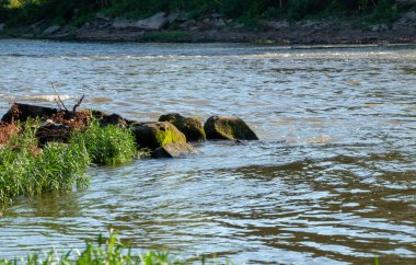 A group of boulders in the waters edge at this Kansas river provide a look at nature with a feeling of peace and serenity. Bokeh effect.
