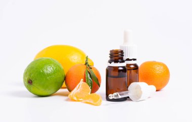 Cam şişede limon yağı ve beyaz arka planda taze yeşil limon meyvesi..