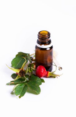 Ayır, yağlı cam şişe ve beyaz arka planda gül kalçası.