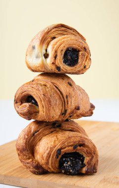 Sarı arka planda katlanmış çikolatalı üç kruvasan.