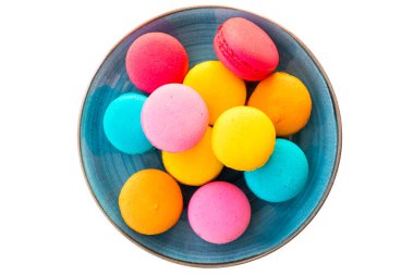 Ahşap bir zeminde mavi bir tabakta duran çok renkli badem kurabiyeleri.