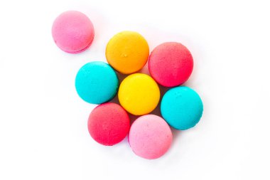 Ahşap bir zeminde mavi bir tabakta duran çok renkli badem kurabiyeleri.