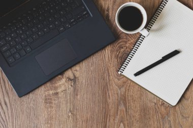 Bilgisayar, tahta arka planda defter-kalem ve kahve