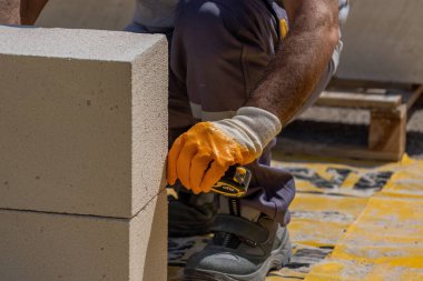 Tuğlacı çalışıyor. Havalandırmalı betondan bir duvar inşa etmek. Gasbeton duvarı