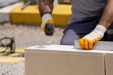 Tuğlacı çalışıyor. Havalandırmalı betondan bir duvar inşa etmek. Gasbeton duvarı