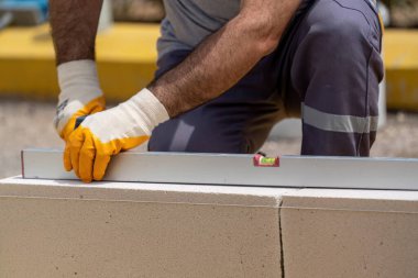 Tuğlacı çalışıyor. Havalandırmalı betondan bir duvar inşa etmek. Gasbeton duvarı