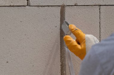Tuğlacı çalışıyor. Havalandırmalı betondan bir duvar inşa etmek. Gasbeton duvarı