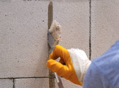 Tuğlacı çalışıyor. Havalandırmalı betondan bir duvar inşa etmek. Gasbeton duvarı