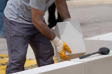 Tuğlacı çalışıyor. Havalandırmalı betondan bir duvar inşa etmek. Gasbeton duvarı
