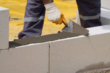 Tuğlacı çalışıyor. Havalandırmalı betondan bir duvar inşa etmek. Gasbeton duvarı