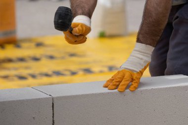 Tuğlacı çalışıyor. Havalandırmalı betondan bir duvar inşa etmek. Gasbeton duvarı