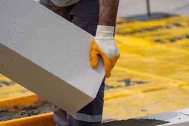 Tuğlacı çalışıyor. Havalandırmalı betondan bir duvar inşa etmek. Gasbeton duvarı