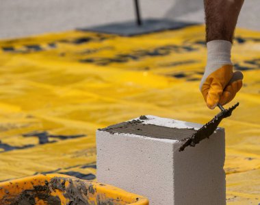 Tuğlacı çalışıyor. Havalandırmalı betondan bir duvar inşa etmek. Gasbeton duvarı