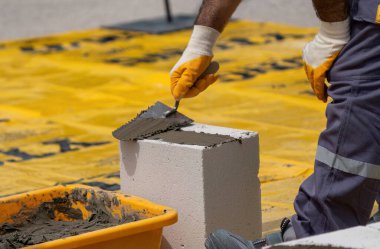 Tuğlacı çalışıyor. Havalandırmalı betondan bir duvar inşa etmek. Gasbeton duvarı
