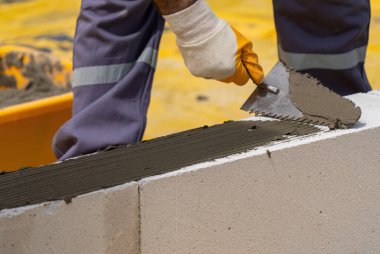 Tuğlacı çalışıyor. Havalandırmalı betondan bir duvar inşa etmek. Gasbeton duvarı