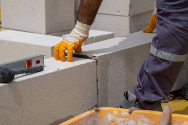 Tuğlacı çalışıyor. Havalandırmalı betondan bir duvar inşa etmek. Gasbeton duvarı