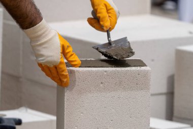 Tuğlacı çalışıyor. Havalandırmalı betondan bir duvar inşa etmek. Gasbeton duvarı