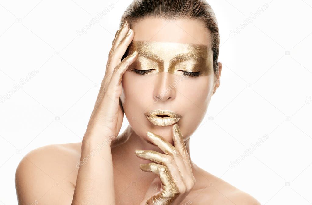 Gold based anti aging skincare concept. Beautiful model woman with gold treatment on a flawless skin posing with closed eyes and a serene expression. Close up beauty portrait isolated on white