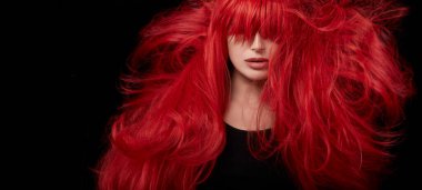 Genç bir kadın uzun ve parlak saçlarını sallıyor. Profesyonel kızıl saç rengine boyanmış. Siyah arkaplanda izole edilmiş yakın plan portresi