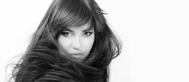 Tek renkli güzel bir kadın, uzun, parlak, sağlıklı siyah saçlarıyla omzunun üstünden süpürülmüş, beyaz tenli, saç bakım konsepti olan bir kadın..